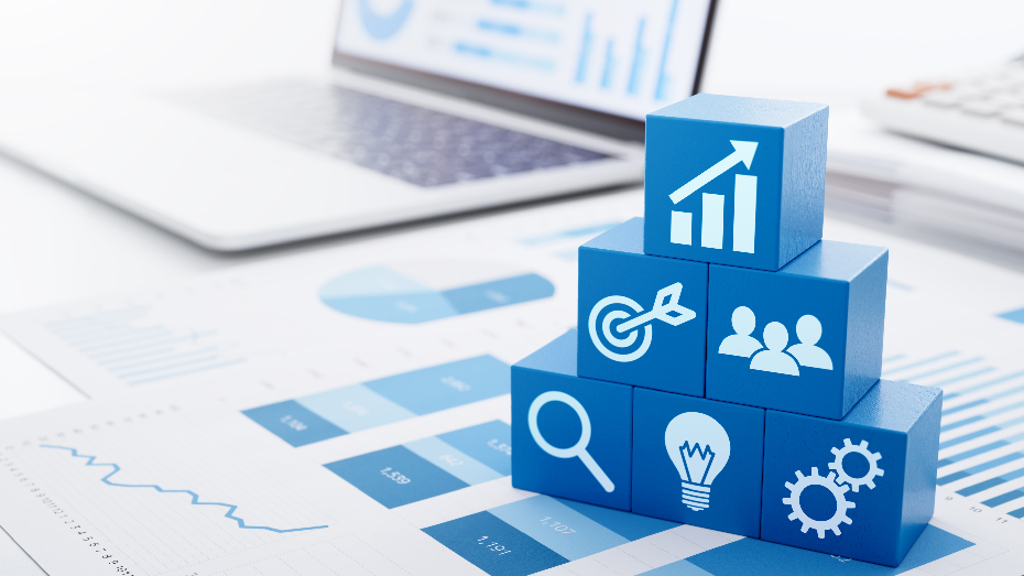 Foto de uma mesa de escritório forrada com papéis e alguns blocos com diferentes ícones formando uma pirâmide.