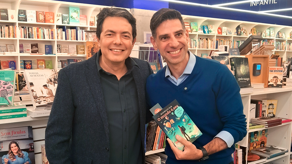 Dib ao lado de Alan Severiano, segurando o livro "O mundo é seu, mas calma lá", em uma livraria
