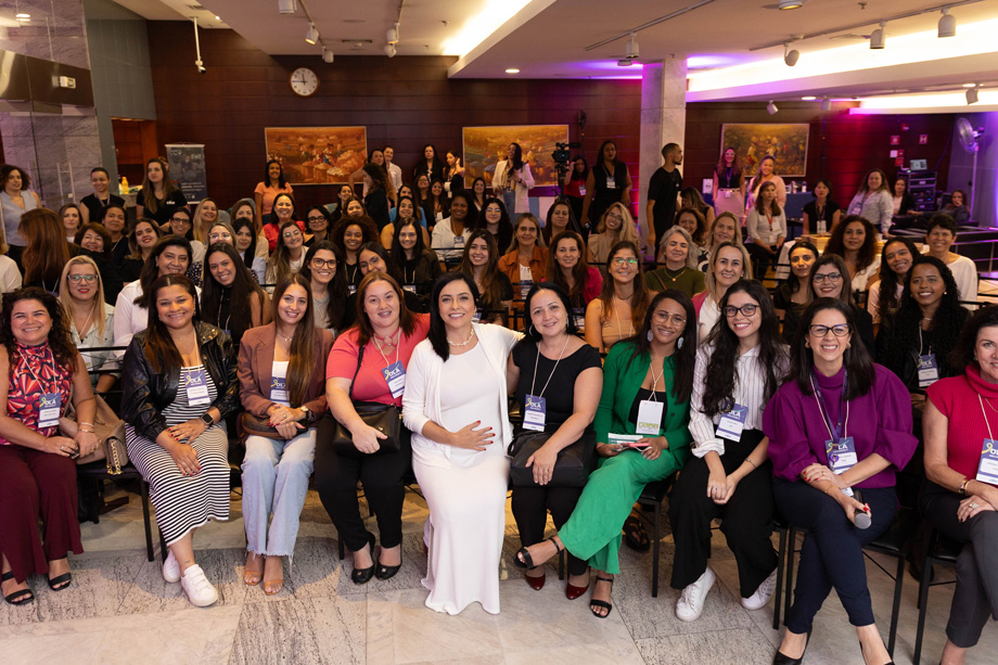 Diversas pessoas no espaço do Foyer do CIEE, todas estão sentadas e olhando para a camera sorrindo