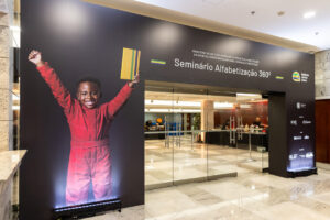Mostra a entrada do Foyer decorada para um evento do Instituto Ayrton Senna. Há uma criança sorridente.