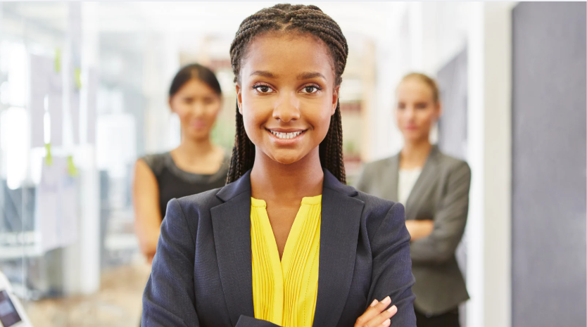 a imagem mostra uma mulher de braços cruzados e sorrindo em uma empresa fazendo estágio para pós-graduação