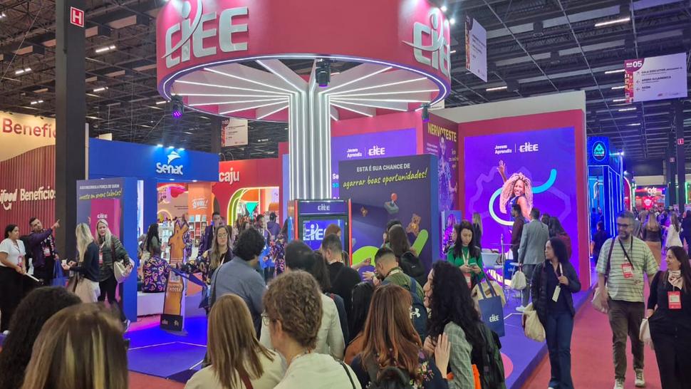 Imagem do estande do CIEE no CONARH, mostra uma estrutura nas cores rosa, com o topo redondo e muitas pessoas aos arredores