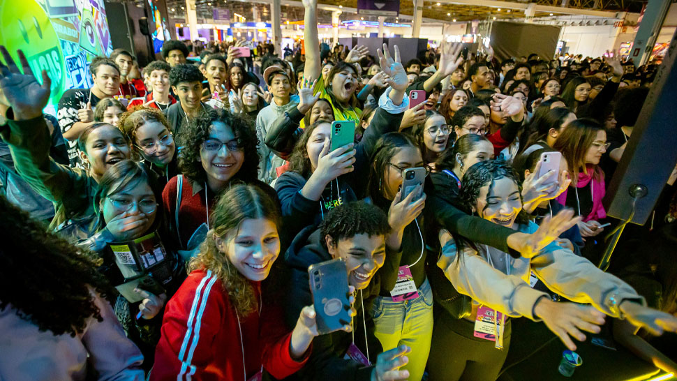 Diversos jovens empolgados com show próximos a grade,