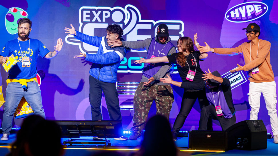 Jovens dançando em um palco com o fundo roxo