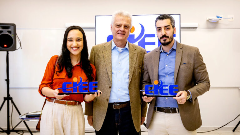 Três pessoas posam para a foto. Dois homens e uma mulher. Casagrande se encontra no meio dos dois. Seguram um totem do CIEE